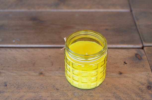 Citronella candle in a glass jar on a wooden table