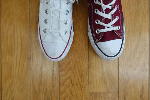Odd shoes, one red and one white canvas sneaker