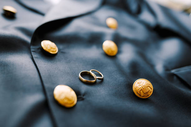 Two gold wedding rings on a blue men's jacket with buttons with a double-headed eagle. High quality photo