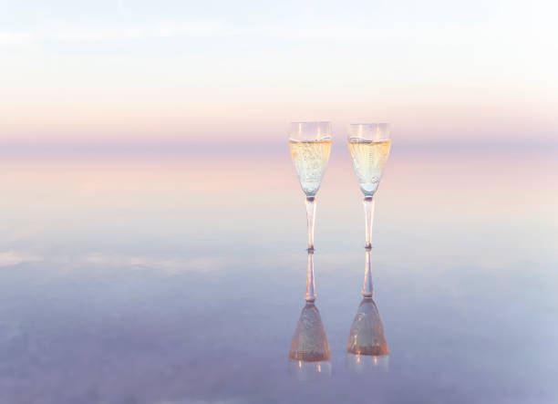 Two glasses of champagne in the water of pink lake with reflaction \