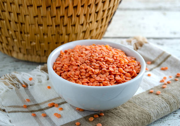 Bowl of Organic Red Lentils Organic red lentils in a white bowl on napkin.  Close up horizontal composition. soup lentil healthy eating dishware stock pictures, royalty-free photos & images