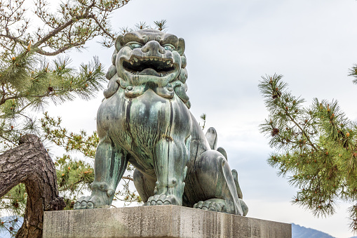 Miyajima Island, Hiroshima, Japan - 13 April, 2019: Bronze lion guardian statue in the streets of Miyajima island. Itsukushima has a number of temples and is located in the northwest of Hiroshima Bay.