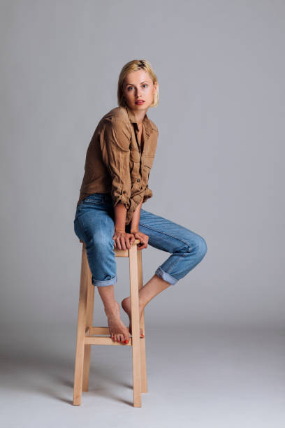 Perfection in woman form Female blond model sitting on a high chair and posing for a studio photo photo studio model stock pictures, royalty-free photos & images