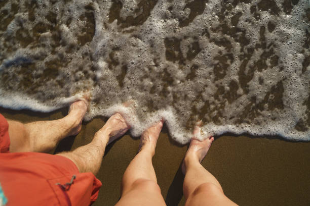 istock Top view on naked feets on sand in foaming sea wave. 1268888929