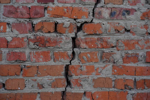 istock Rough aged masonry background. Backdrop of old red bricks with shabby texture and with a crack 1268894355