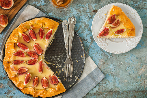 Freshly baked crostata with mascarpone cheese, figs and honey on rustic background