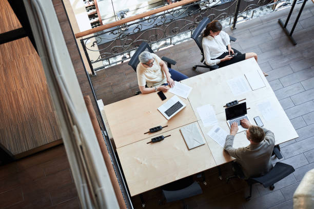 istock Two women and a man sharing a table at a coworking 1268902122