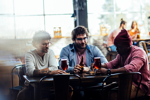 Three male friends having drinks at a bar