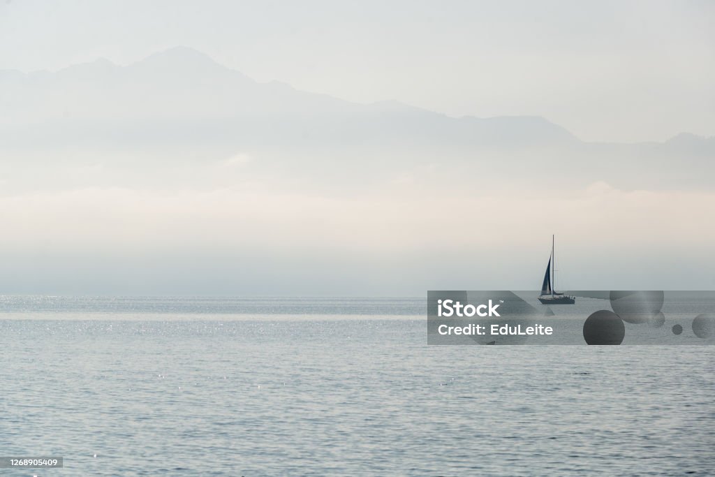 Sailboat on a foggy morning Sailboat on a foggy morning on lake Geneva Desaturated Stock Photo