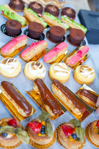 Sweets-tartlets with fruit jelly and fruit slices:strawberries, blueberries, physalis berries, eclairs with chocolate, fountain. Cakes are made by hand by pastry chefs. For sale at a street fair.