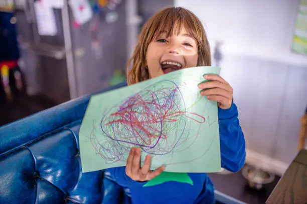 Photo of Child holds up drawing she made