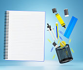 The stationary or office equipment and blank notebook floating on a blue background.