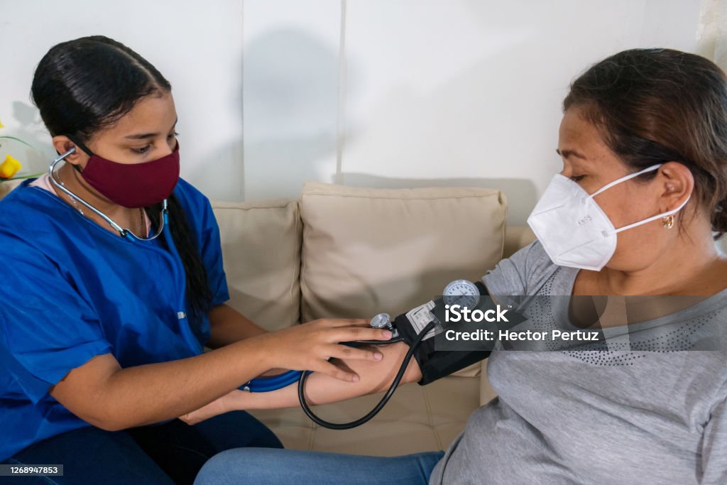 A doctor wearing a mask who measures a patient's blood pressure Diabetes Stock Photo