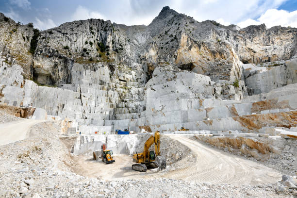Landscape view of an open cast marble quarry Landscape view of an open cast marble quarry in Carrara, Tuscany, Italy showing the heavy duty equipment and rock face quarry stock pictures, royalty-free photos & images