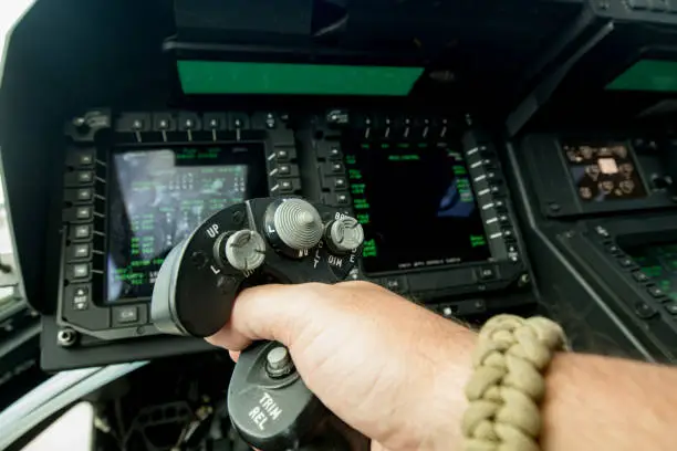 A close up of a hand on a control stick in the cockpit of a mv 22 Osprey.