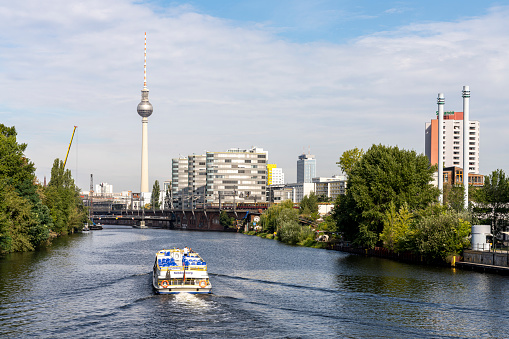 Berlin, Germany - August 20, 2020: A river cruise boat sailing north west on the Spree river, with the TV tower in the background, in Berlin, Germany