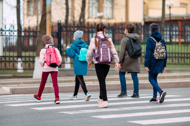 School children cross the road in medical masks. Children go to school. stock photo