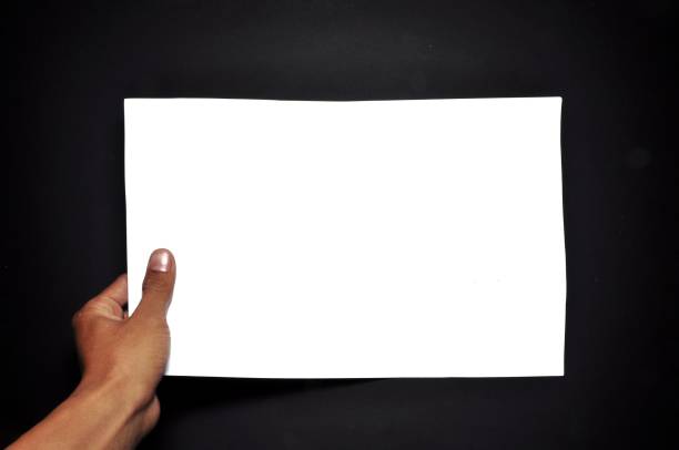 istock Hand holding white paper isolated on black background. Close-up hand holding blank sheet 1269019216