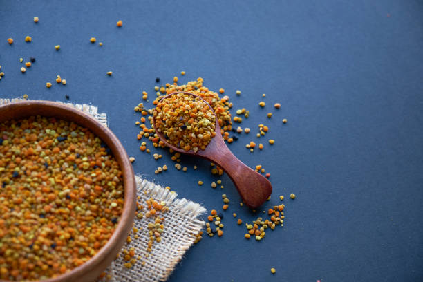 Bee pollen in a wooden spoon healthy food supplements. Close up on a black background. Top view, flat lay. copy space for text stock photo