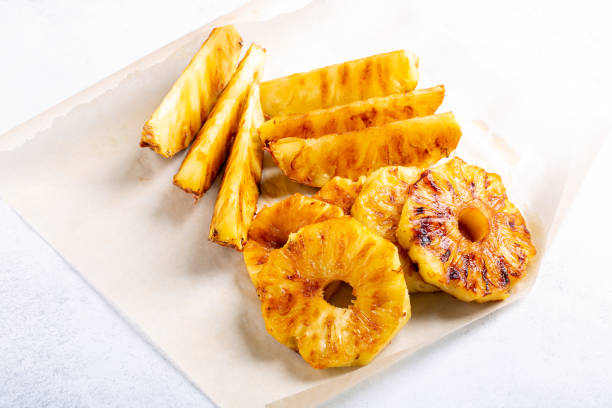 istock Heap of grilled pineapple slices on white background. 1269024190