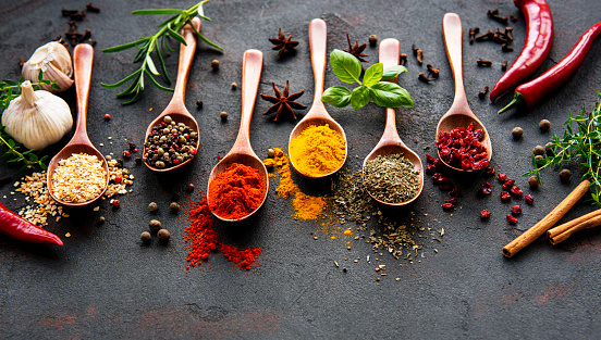 Different assortment of spices on black stone background. Top view.
