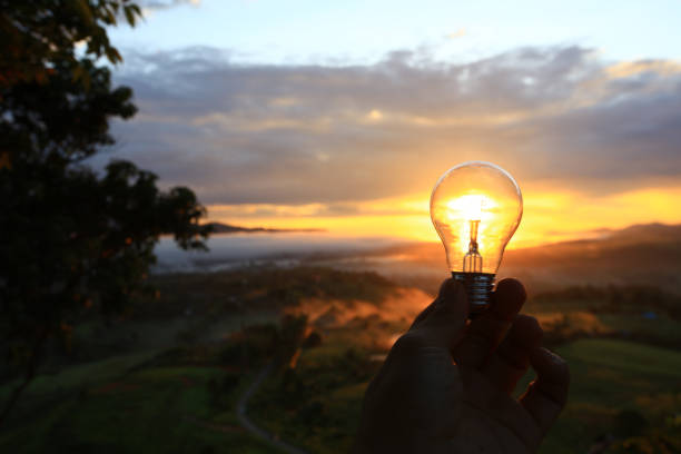 Hand holding a light bulb at sunset,  eco or engergy saving concept