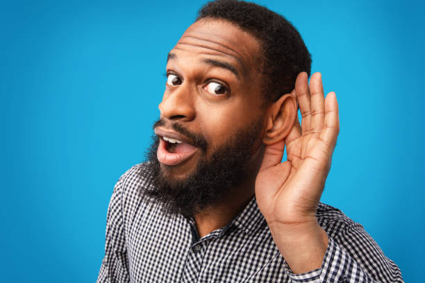 istock Curious handsome afro guy holding hand near his ear 1269028595