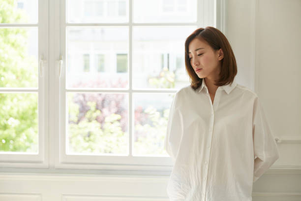 young asian woman standing by window at home