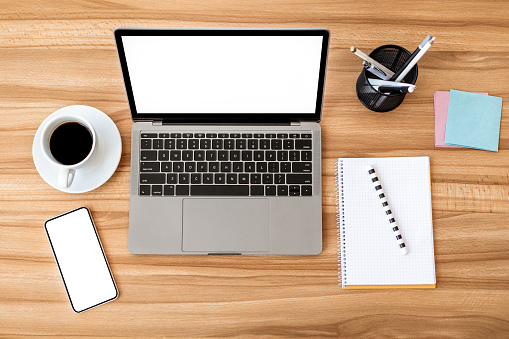 Office Workplace. Flat lay of laptop and cell phone with white monitors for mock up, notebook and coffee on the table