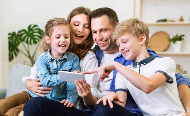 istock Parents And Kids Using Cellphone Sitting On Couch At Home 1269029738