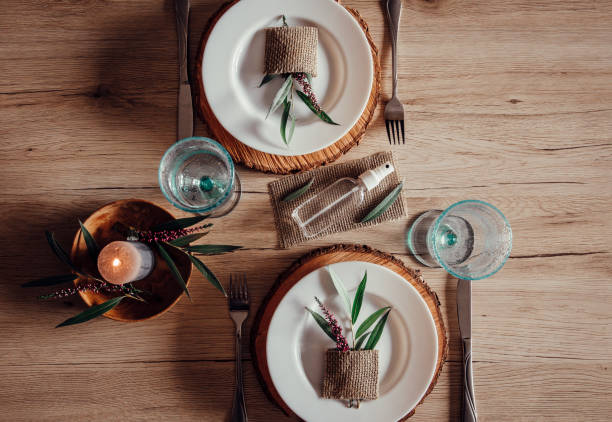 istock Restaurant table set with hand sanitizer bottle in center. White plates with leaf and heather flower decoration. Virus spreading prevention, new reality. 1269031297