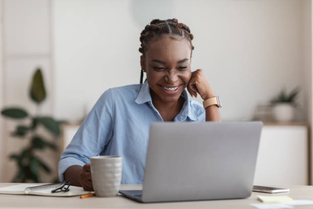 istock Smiling Black Female Employee Using Laptop And Drinking Coffee At Office Workplace 1269033145