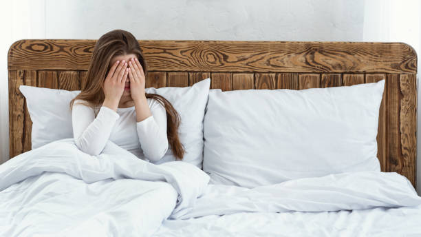 istock Sad woman covers her face with hands and sits in bed 1269034554
