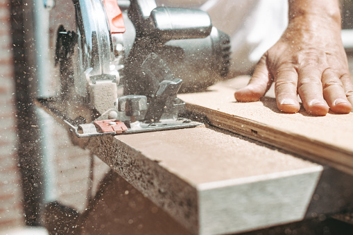 Carpenter usando sierra de potencia circular para cortar madera, mejora del hogar, hacerlo usted mismo (DIY) y concepto de obras de construcción, toma de acción photo