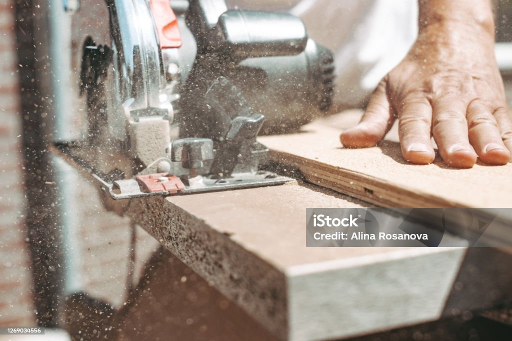Carpenter using circular power saw for cutting wood, home improvement, do it yourself (DIY) and construction works concept, action shot Carpenter Stock Photo