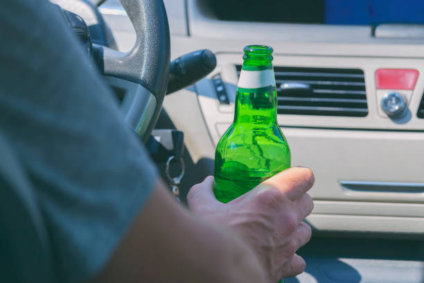 Man drinking beer in a car Man holding green bottle of beer in hand while driving a car. Don't drink and drive concept alcoholism alcohol addiction drunk stock pictures, royalty-free photos & images