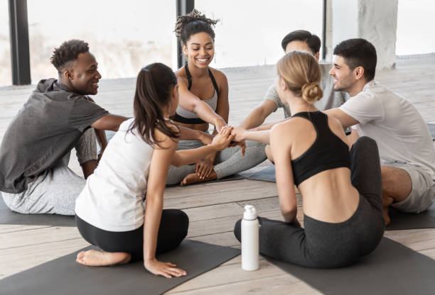 istock Teamwork and unity. Diverse yoga class friends putting hands together after training 1269035924