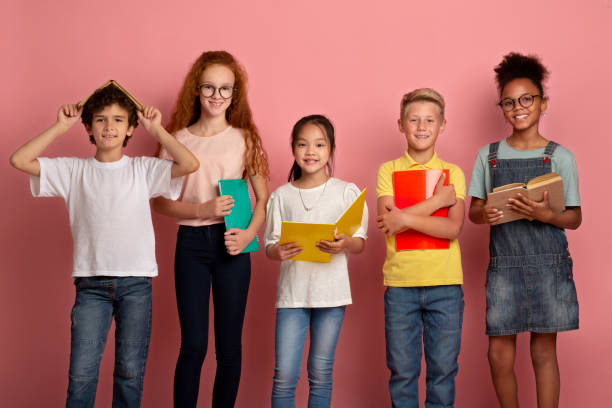 istock Multinational group of kids with books and notebooks ready for school on pink studio background 1269036076