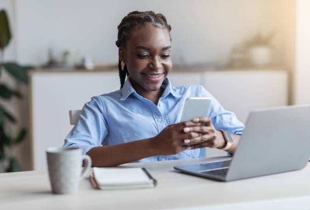istock Black female employee using mobile phone at workplace in office, having break 1269036364