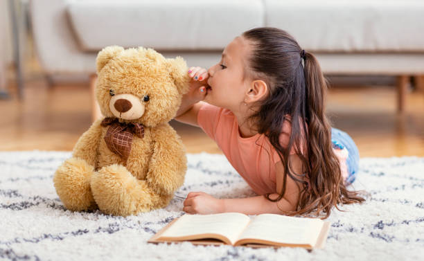 asian kid girl sharing secret with teddy bear at home - segredo criança imagens e fotografias de stock