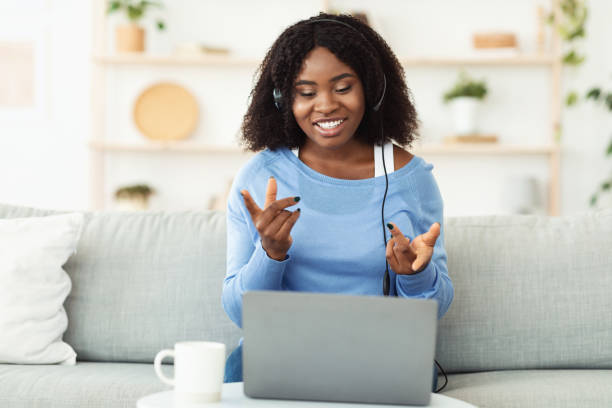 istock Smiling black woman sitting on couch with headset 1269046080