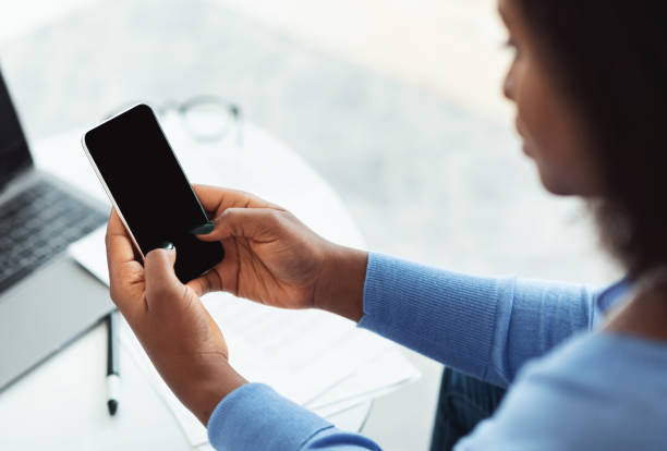 istock Back view of black girl sitting on sofa, using phone 1269047512