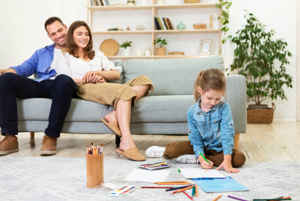 istock Relaxed Parents Sitting On Sofa Looking At Daughter Drawing Indoor 1269050290