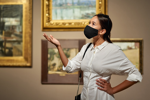 woman visitor wearing an antivirus mask in the historical museum looking at pictures