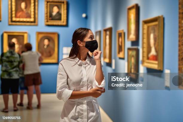 Woman Visitor Wearing An Antivirus Mask In The Historical Museum Looking At Pictures Stock Photo - Download Image Now