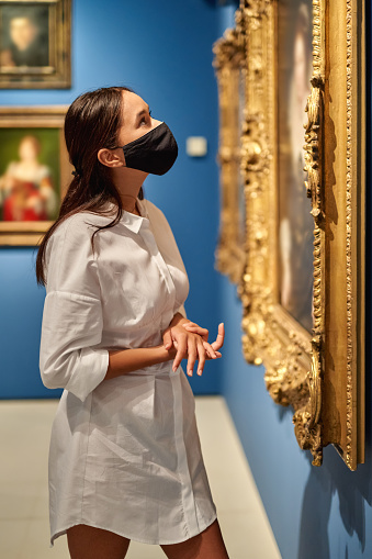 woman visitor wearing an antivirus mask in the historical museum looking at pictures