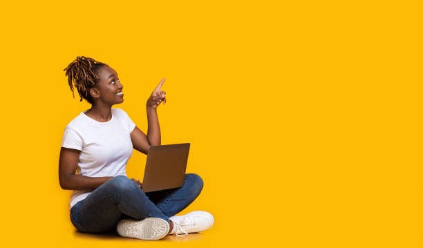 istock Young african woman with laptop pointing at empty space 1269057208