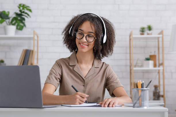 istock Stay home and study online. Friendly girl makes notes in notebook and listens to webinar on laptop 1269062131