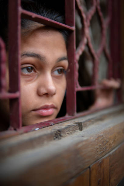istock sad young girl looking out through the window and thinking. 1269062795