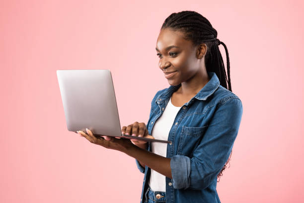 istock Black Student Girl Holding Laptop Computer Standing On Pink Background 1269063567